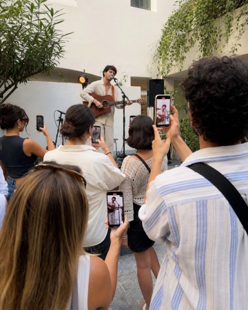 A musician playing while the crowd films from several angles